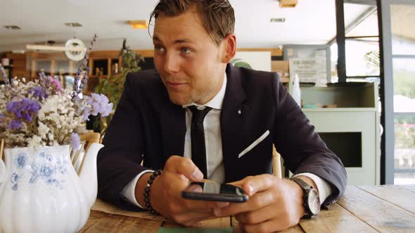 Businessman Smiling And Holding Smartphone On Table In Cafe