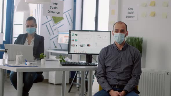 Portrait of Businessman with Protective Face Mask While Sitting in Startup Corporate Office