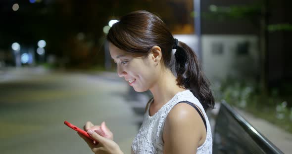 Woman use of mobile phone at outdoor in the evening