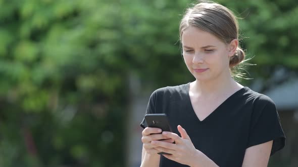 Young Happy Beautiful Woman Smiling While Using Phone Outdoors