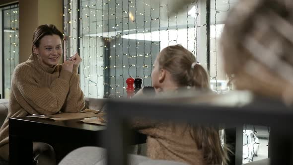 Mother and Daughter Sit in a Cafe in Sweaters of the Same Color