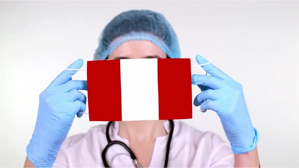 Close-up. Doctor in Glasses, Blue Medical Cap, Gloves Holds in Hands Medical Mask with Peru Flag