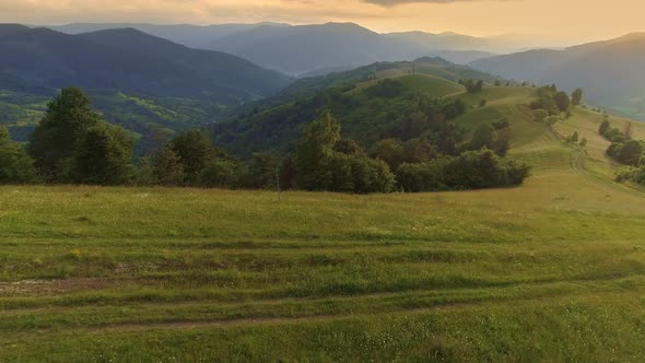 Aerial View of Rural Road Along the Ridge of Green Hill. Mountains and Meadows Covered with Flowers