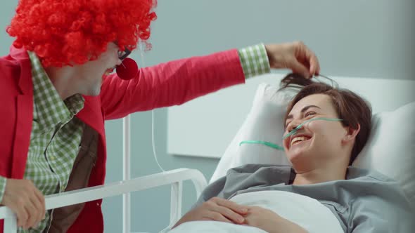 Clown Entertaining Female Patient in Hospital Ward