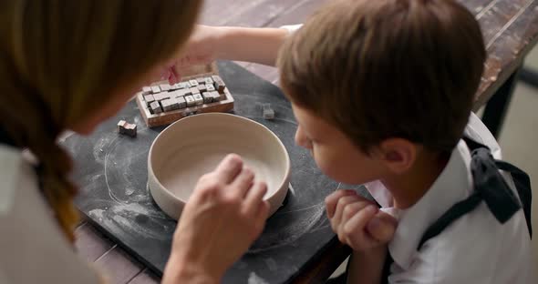 Mom and Her Son Draw a Clay Bowl Together in a Pottery Studio Workshop