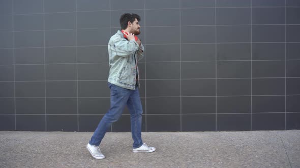 Man puts on red headphones connected to a red mobile phone and begins to walk with rhythm and dance