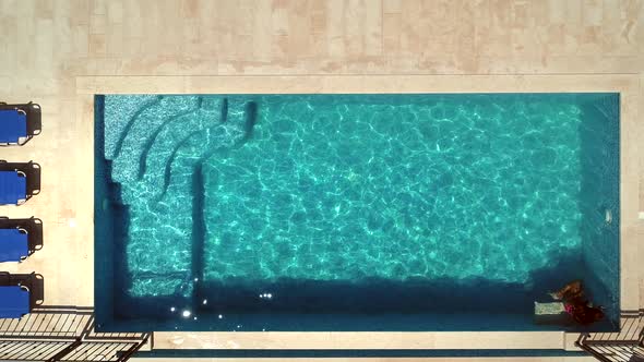 Aerial view of young girl jumping into swimming pool.