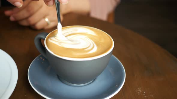 Person Hand Stirring Coffee with Spoon