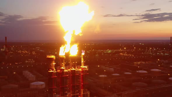 Flare Stacks of the Oil Refinery are Emitting Fire at Sunset