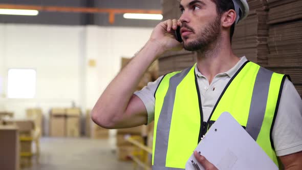 Warehouse worker talking on the phone holding clipboard