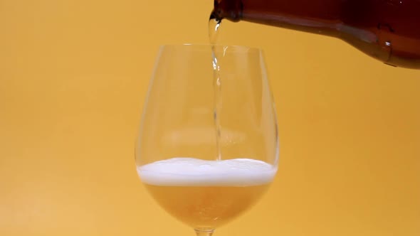 Pouring Beer Slow Motion To The Glass Close Up Angle On Yellow Bg