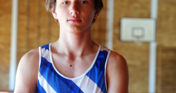 Portrait of schoolboy standing in basketball court