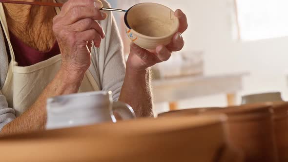 Female potter painting a bowl