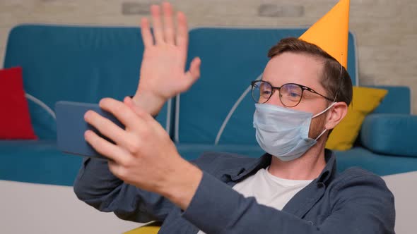 A Young Man with a Birthday Hat and a Medical Mask on His Face Talks Online with His Friends.