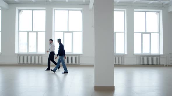 Real Estate Agent Walks with Client Around an Office Space for Rent Side View