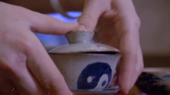 Closeup Master Pouring Infusion Tea From Gaiwan in Fairness Bowl at Tea Ceremony