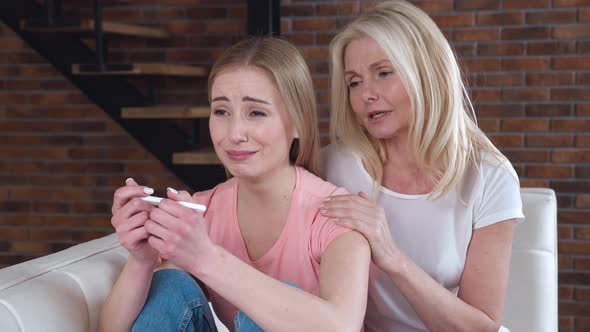 Young Adult Woman is Suffering and Crying From an Unwanted Pregnancy Holding a Pregnancy Test in Her