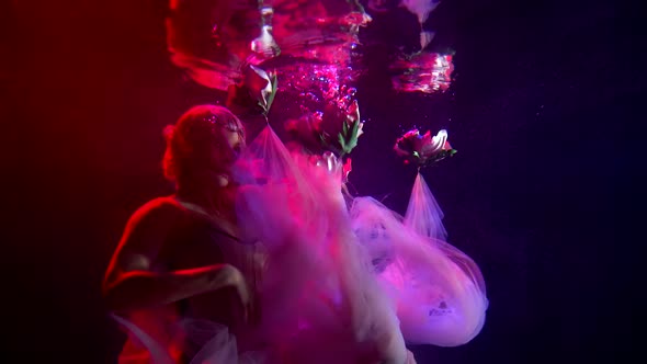 A Girl Is Under Water, She Is Illuminated By Pink Lighting, Her Train of Dress Is Fluttering Under