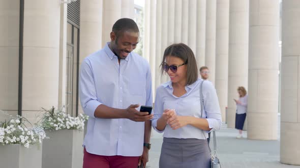 African Business Couple Walking Outdoors and Using Smartphone