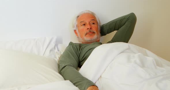 Senior man relaxing on bed in bedroom 4k