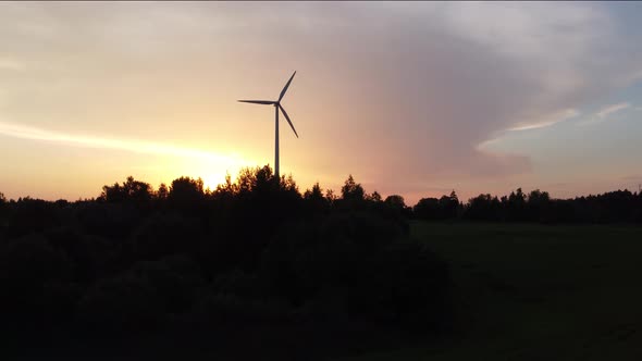 Silhouette of a Wind Turbine behind the Contours of the Trees