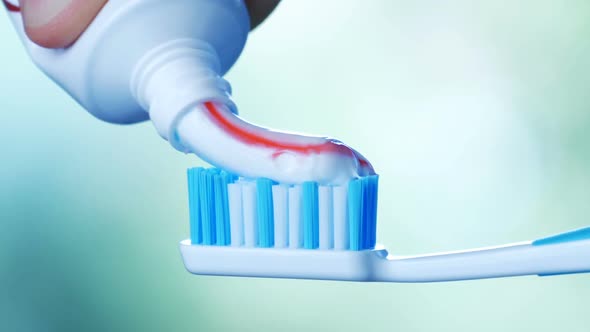 Dental Health - Squeezing Toothpaste with Colorful Stripes From a Tube Onto a Toothbrush.