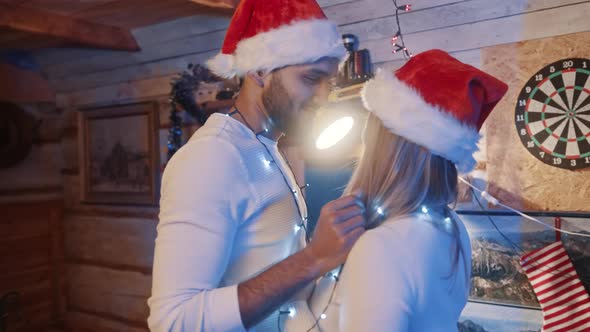 Happy Young Couple Dancing with Christmas Lights and Santa Hats