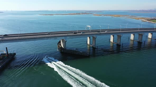 An aerial drone shot over Jamaica Bay in Queens, NY. The camera dolly in following a boat which goes