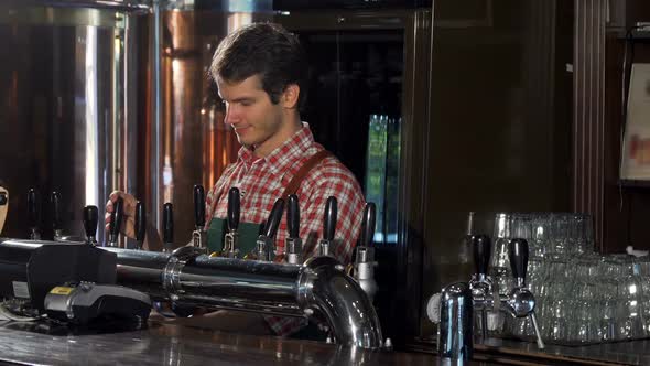 Male Bartender Pouring and Serving Delicious Craft Beer at His Pub