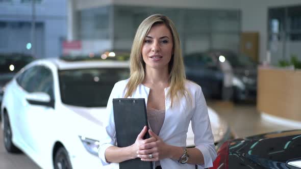 Portrait of Smiling Woman Advertising Brand New Vehicles Talking Looking at Camera Standing in Car