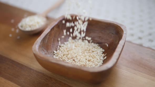 White Sesame Seeds In Wooden Bowl And Spoon. Slow Motion.