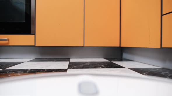 POV View of Robot Vacuum Cleaner Cleans Tiles Floor in House at Kitchen