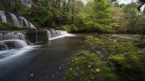 Panorama motion time lapse of forest waterfall in rural landscape during autumn in Ireland.