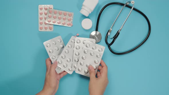 two womens hands put on a blue table packing pills in a blister