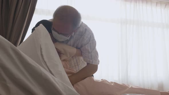 Asian young little girl kid wearing mask lying on bed in recovery room, feel happy for family visit.