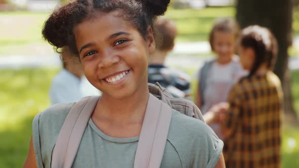 Portrait of Joyous Afro-American Schoolgirl Smiling at Camera in Park