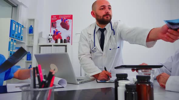 Man Doctor Giving Radiography to Senior Coworker