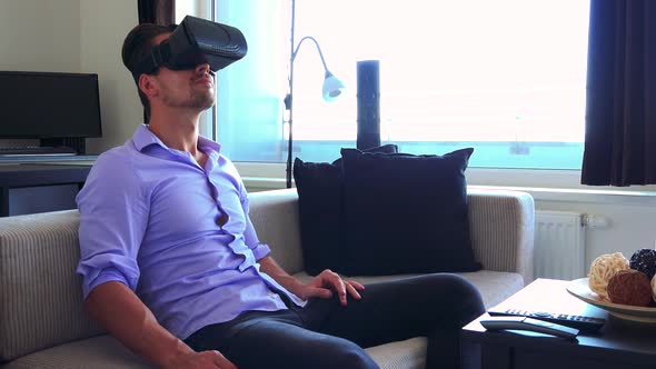 Young Handsome Man Uses Virtual Reality Glasses in Home, in Living Room