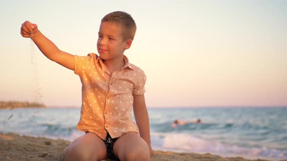 Child Playing with Sand By the Sea at Sunset