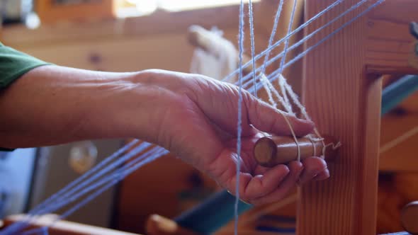 Senior woman placing woollen thread on weaving machine 4k