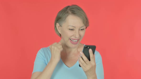 Old Woman Celebrating on Smartphone on Red Background