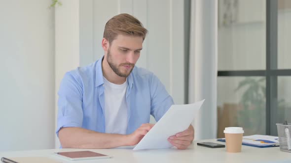 Young Creative Man Celebrating Success While Reading Documents