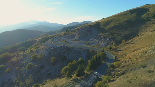 Drone Following Heavy Cargo Truck or Lorry on Winding Rocky Mountain Road