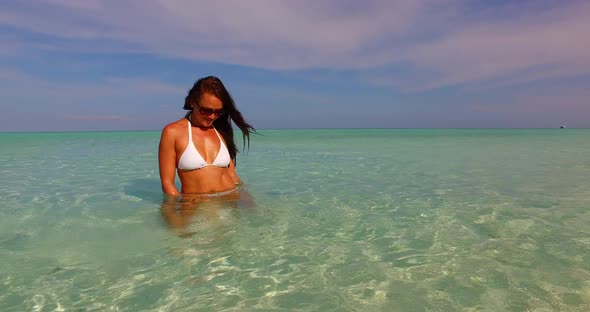 Young smiling girl on vacation having fun at the beach on clean white sand and blue 