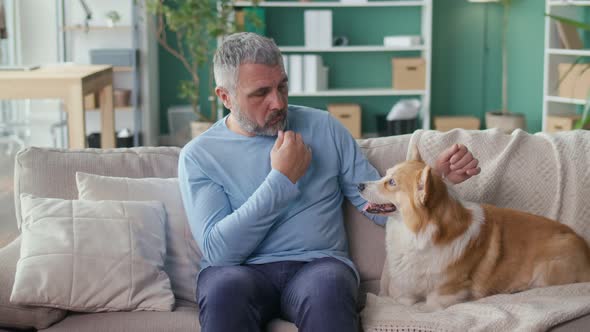 Sad Elderly Man Stroking His Dog While Sitting on the Couch Feeling Lonely