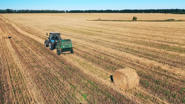 Tractor Is Riding Along the Field with a Pile of Hay on It