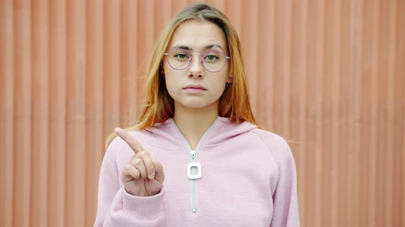 Slow Motion Portrait of Serious Young Lady Shaking Finger Warning and Looking at Camera Outdoors