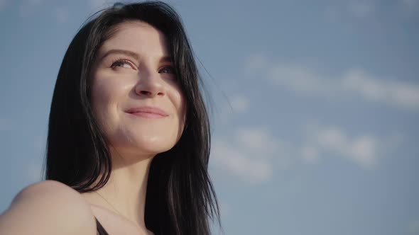 Close-up Face of Beautiful Brunette Woman with Grey Eyes Enjoying Summer Day Outdoors. Portrait of