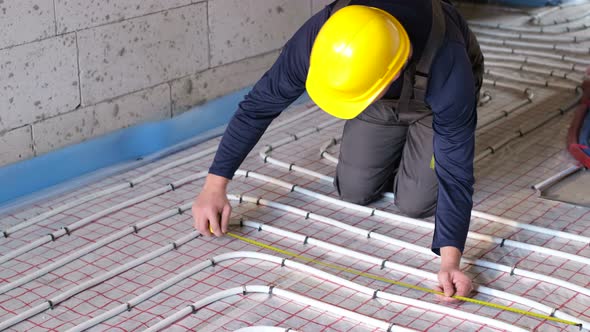 A Professional Worker Arranges Water Heating on the Floor in the House