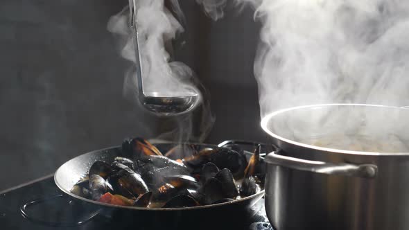 Cooking Delicious Seafood Pasta with Mussels in Frying Pan. Shot in Slow Motion. Broth Being Poured